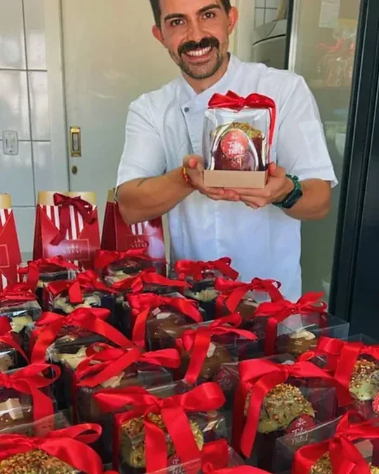 Confeiteiro com as encomendas de Natal embaladas e um ovo de colher decorado